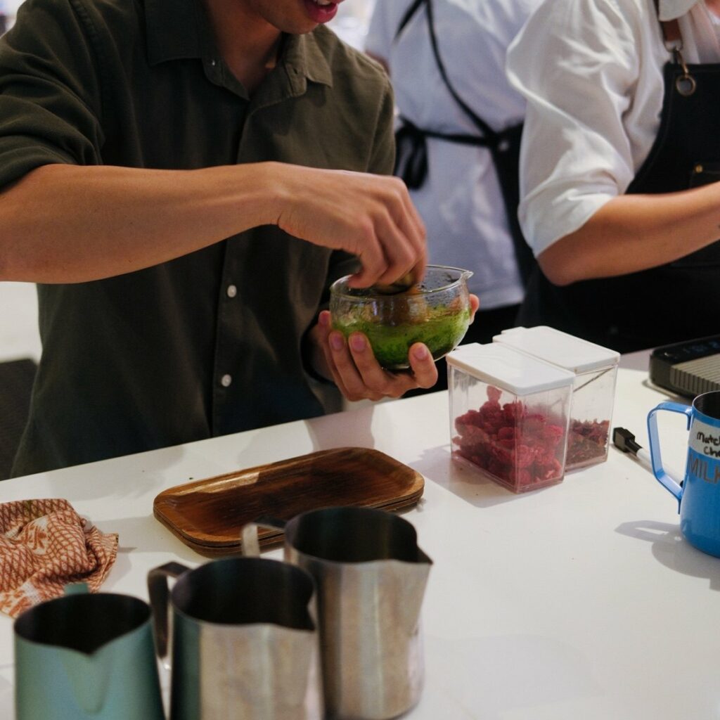 Baristas building several matcha drinks on a cafe bench